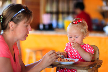 mother feeding infant daughter in cafe