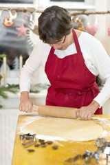 Frau mit roter Schürze backt Plätzchen in ihrer Küche