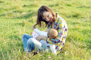 Fototapeta premium Young Mom breastfeeding her baby outdoors