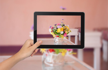 Female hand holding tablet PC with flower pictures on the screen