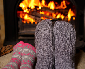 Mom and daughter warm their socked feet by the fire