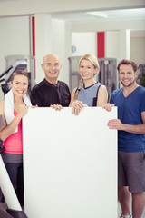gruppe im fitness-studio zeigt ein weißes schild