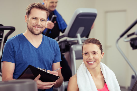 trainer und zufriedene kundin im fitness-studio