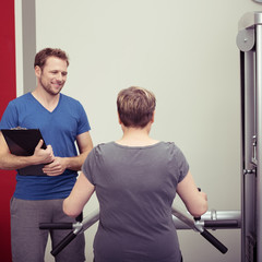 trainer betreut eine ältere frau beim krafttraining
