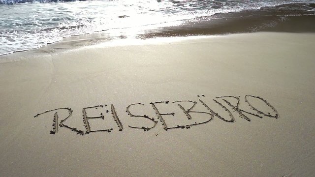 Wort Reisebüro in Sand gezeichnet