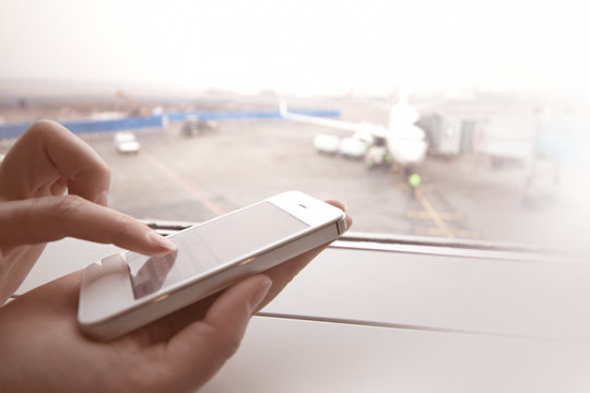 Woman using smart phone by the window at aiport