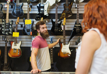 assistent die de gitaar van de klant laat zien in de muziekwinkel