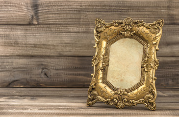 Golden baroque picture frame on wooden background