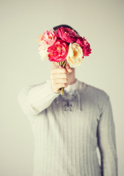 man covering his face with bouquet of flowers