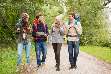 group of smiling friends with backpacks hiking