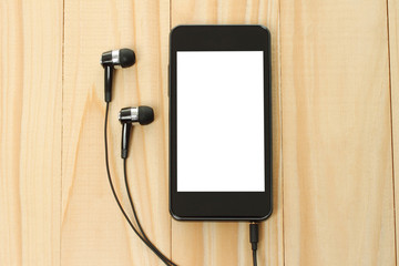 Smart phone with headphones on wooden background.