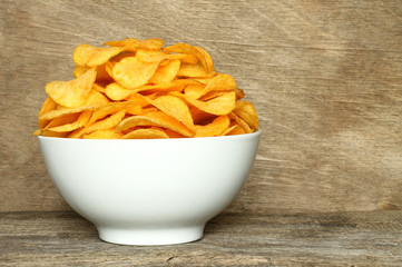 Potato chips bowl on a wooden background .