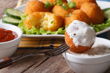Fried potato balls with sour cream close-up horizontal.