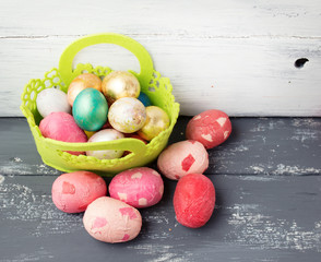 Painted Easter Eggs  in decorated green basket on wooden table.