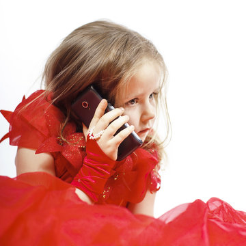 Cute little girl dressed in ball gown playing with smartphone