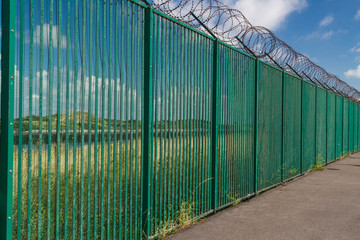 Razor wire on top of green fence guarding French ferry terminal.