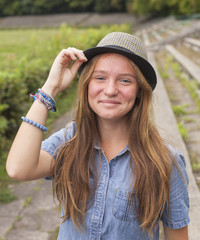 Young cute girl with a hat posing in park.