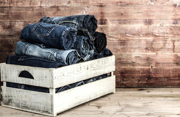 Old  jeans in wooden box over grungy background - 77013309