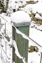 Snow on wooden pole and fence