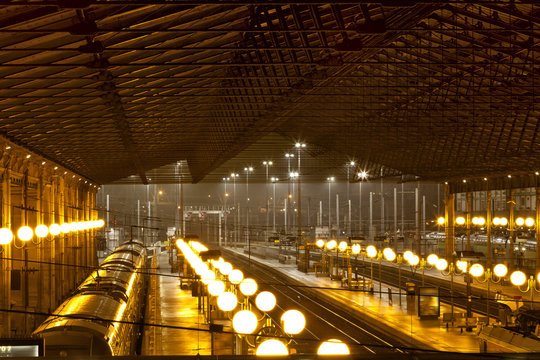 Inside of a train station at night illuminated by rows of lamps