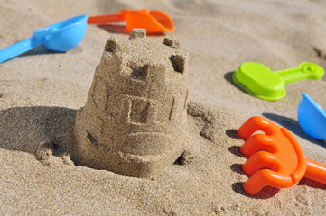 sandcastle and toy shovels on the sand of a beach