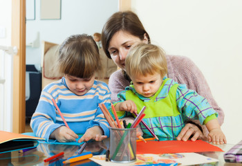 Mother and two children sketching on paper