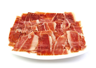 Serrano ham slices on a white dish. Jabugo. Spanish tapa.