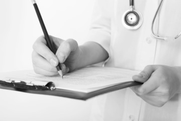 Doctor writing on clipboard on light background