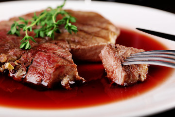 Grilled steak in wine sauce on plate close up