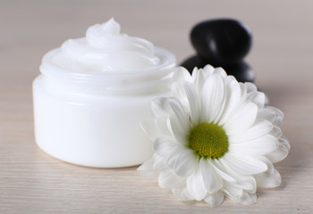 Fototapeta na wymiar Cosmetic cream with spa stones and chamomile