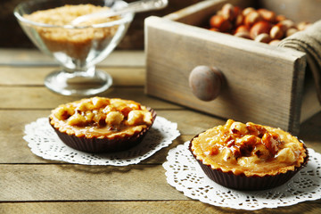 Mini cakes with nuts on napkin on wooden background