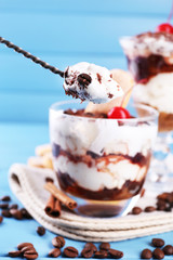 Tasty tiramisu dessert in spoon and glass,