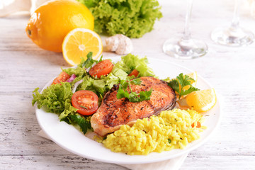 Tasty baked fish with rice on plate on table close-up