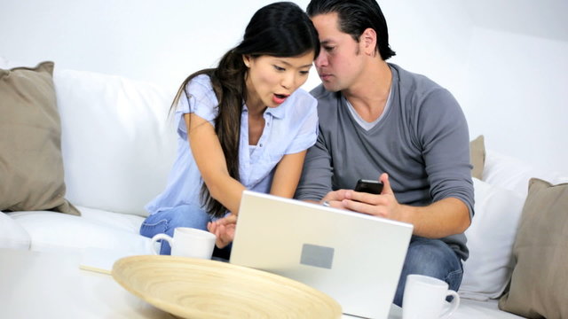 Ethnic Couple Using Wireless Laptop Trying Solve Financial Problems 