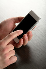 Hands holding smart mobile phone on wooden table background