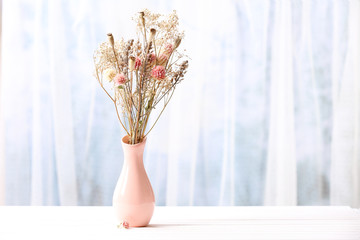Bouquet of dried flowers in vase on light background