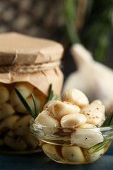 Canned garlic in glass jar on color wooden background