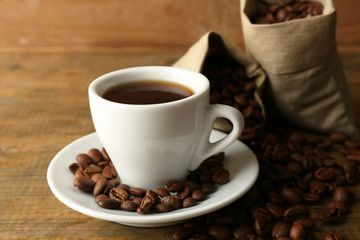 Cup of coffee with beans on rustic wooden background