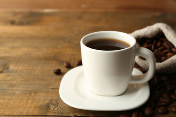 Cup of coffee with beans on rustic wooden background