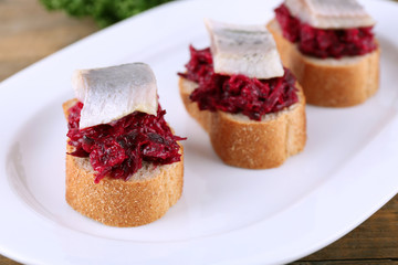 Rye toasts with herring and beets on plate close up