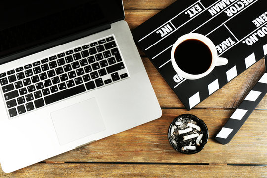 Movie clapper with laptop and cup of coffee on wooden
