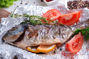 Tasty baked fish in foil on table close-up
