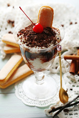 Tasty tiramisu dessert in glass, on wooden background