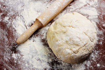 homemade pizza dough with rolling pin on the wooden table