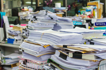 Naklejka premium Pile of documents on desk stack up high waiting to be managed.