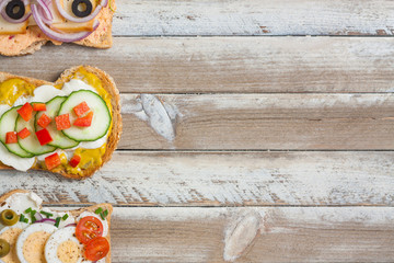Sandwiches on wooden background, empty space on right