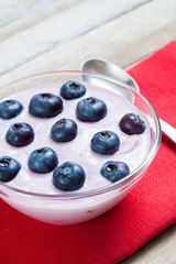 Yogurt with blueberries on red cloth, vertical edit, closeup