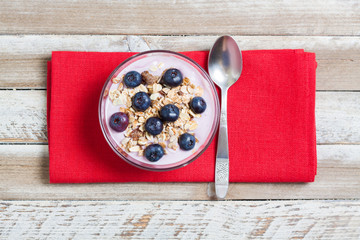 Yogurt with blueberries and muesli on wooden background