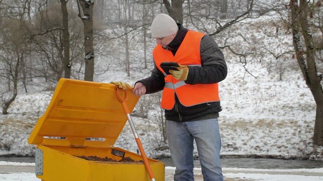 Worker with tablet PC near the sandbox in winter