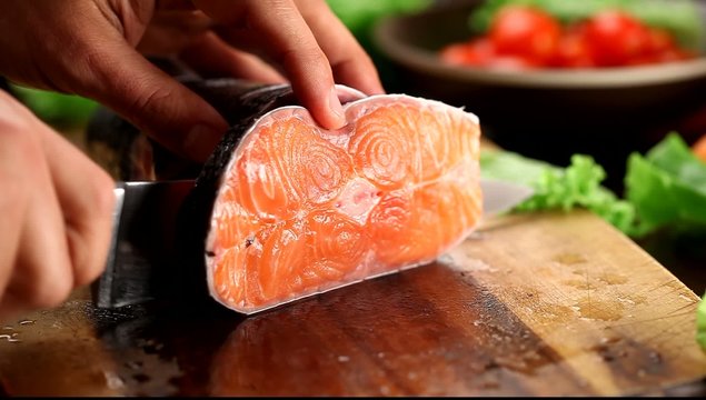 Male hands cutting salmon fish.